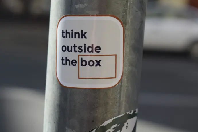 A sticker on a pole that says think outside the box